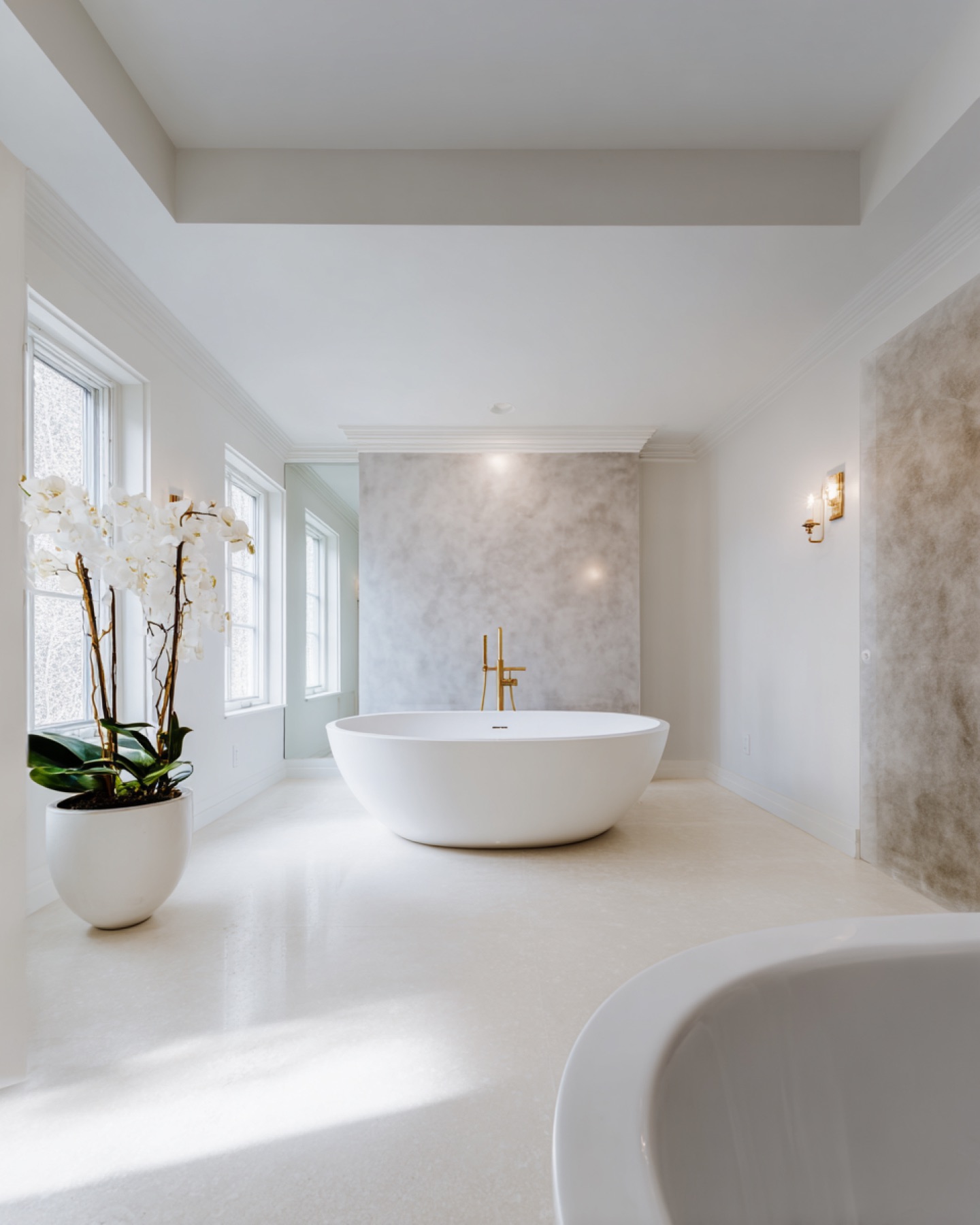 Lichte microcement wand achter freestanding bad in luxe badkamer Utrecht, naadloze afwerking van Hands of Luxury