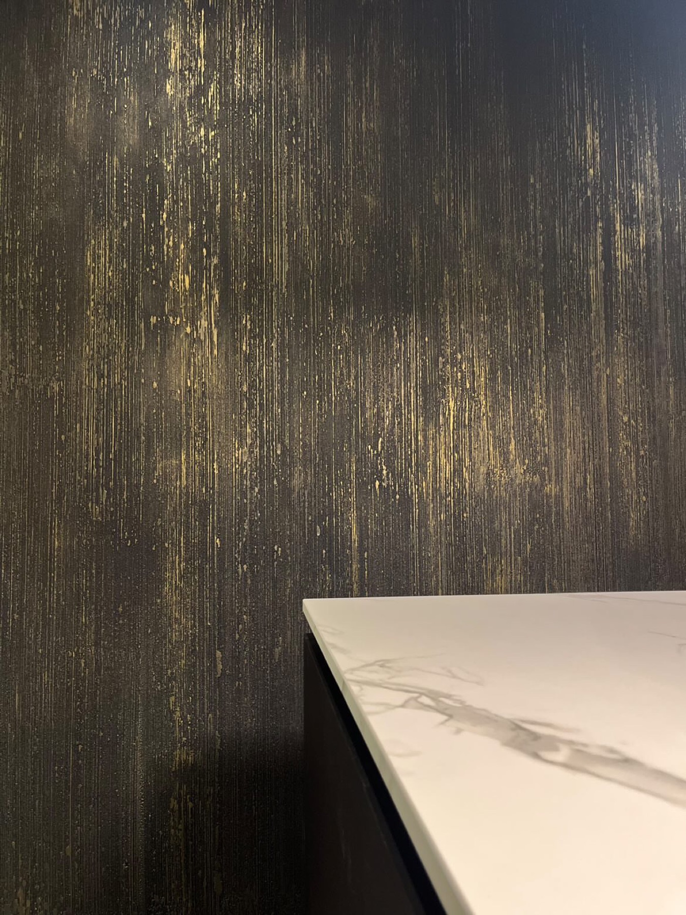 Gocce d'Oro Black & Gold wand met gouden druppeltextuur achter wit-marmeren aanrecht in keuken Laren