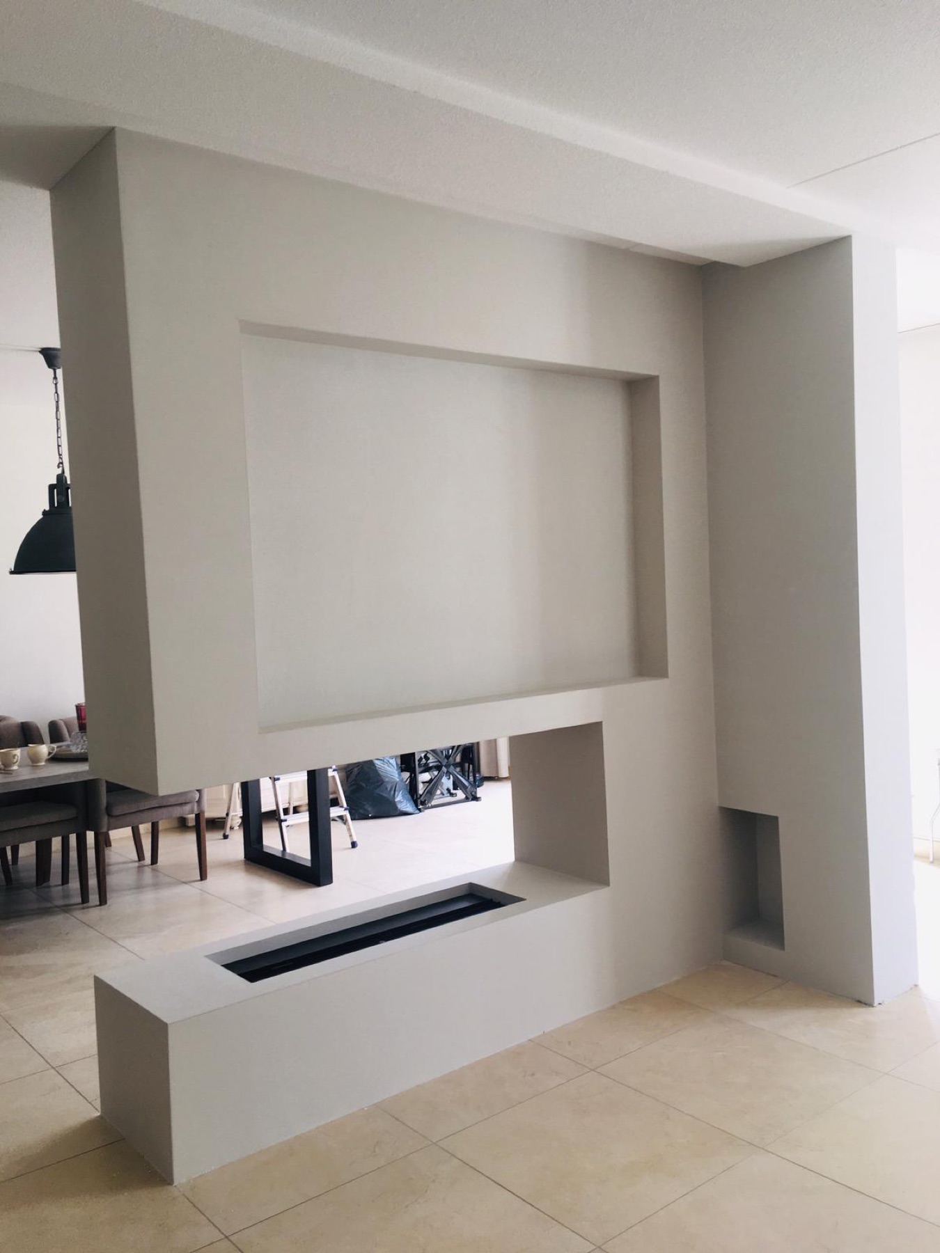 Strak glad sausklaar stucwerk rond ingebouwde TV- en haardniche in nieuwbouwwoning Breda, uitgevoerd onder label Pleisterbaas